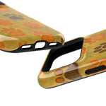 Close-up of two glossy phone cases with orange and brown paw print patterns, showing different sizes