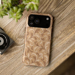 Saddle Scrolls – Tan Western Scrollwork MagSafe Phone Case, glossy wide-camera Pro Max model, rear view on a wooden surface