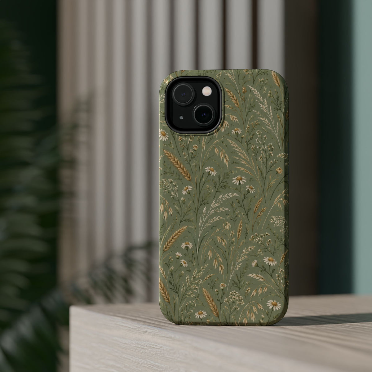 Golden Meadow – Sage Green Wildflower MagSafe Phone Case, glossy diagonal dual-camera model, rear view on a tabletop