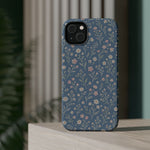 Denim Wildflowers MagSafe Phone Case, glossy diagonal dual-camera model, rear view on a tabletop