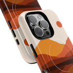 Close-up of two iPhone cases in different variant sizes with orange and brown abstract landscape design