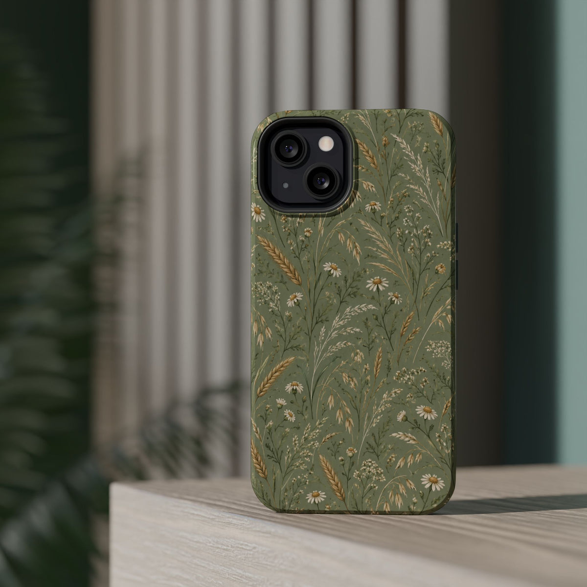 Golden Meadow – Sage Green Wildflower MagSafe Phone Case, glossy diagonal dual-camera model, rear view on a tabletop