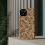 Saddle Scrolls – Tan Western Scrollwork MagSafe Phone Case, glossy diagonal dual-camera model, rear view on a tabletop