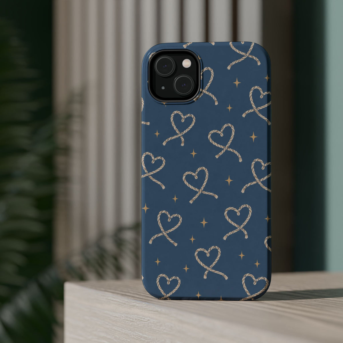 Lasso Hearts – Blue Western Heart MagSafe Phone Case, glossy diagonal dual-camera model, rear view on a tabletop