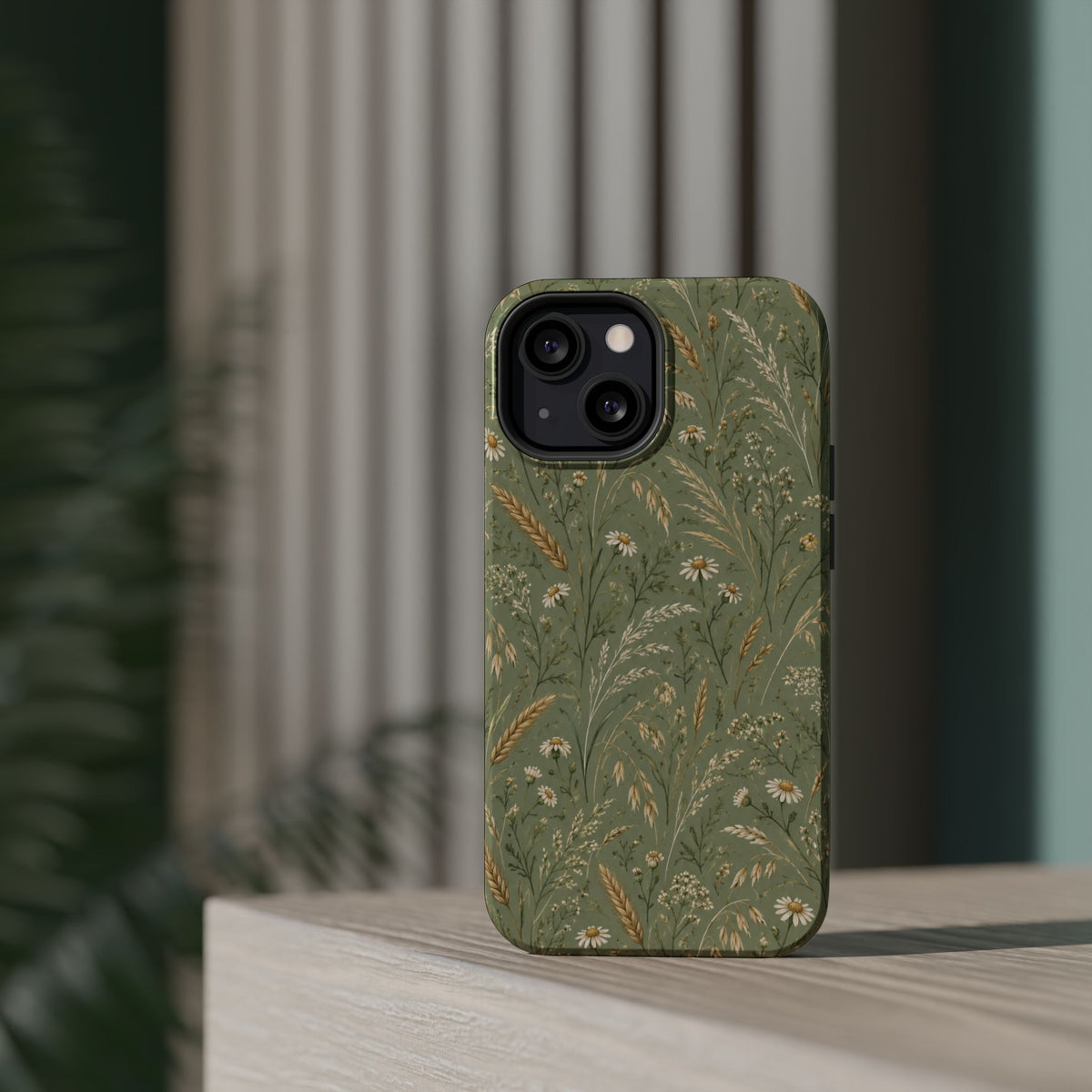 Golden Meadow – Sage Green Wildflower MagSafe Phone Case, glossy diagonal dual-camera model, rear view on a tabletop