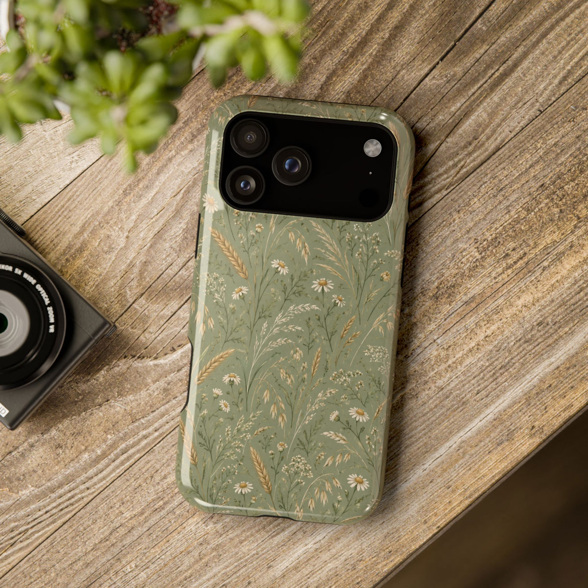Golden Meadow – Sage Green Wildflower MagSafe Phone Case, glossy wide-camera Pro Max model, rear view on a wooden surface