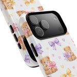 Two smartphone cases with teddy bear and colorful bow design, showing different sizes and camera cutouts