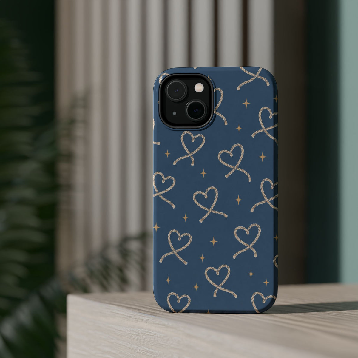 Lasso Hearts – Blue Western Heart MagSafe Phone Case, glossy diagonal dual-camera model, rear view on a tabletop