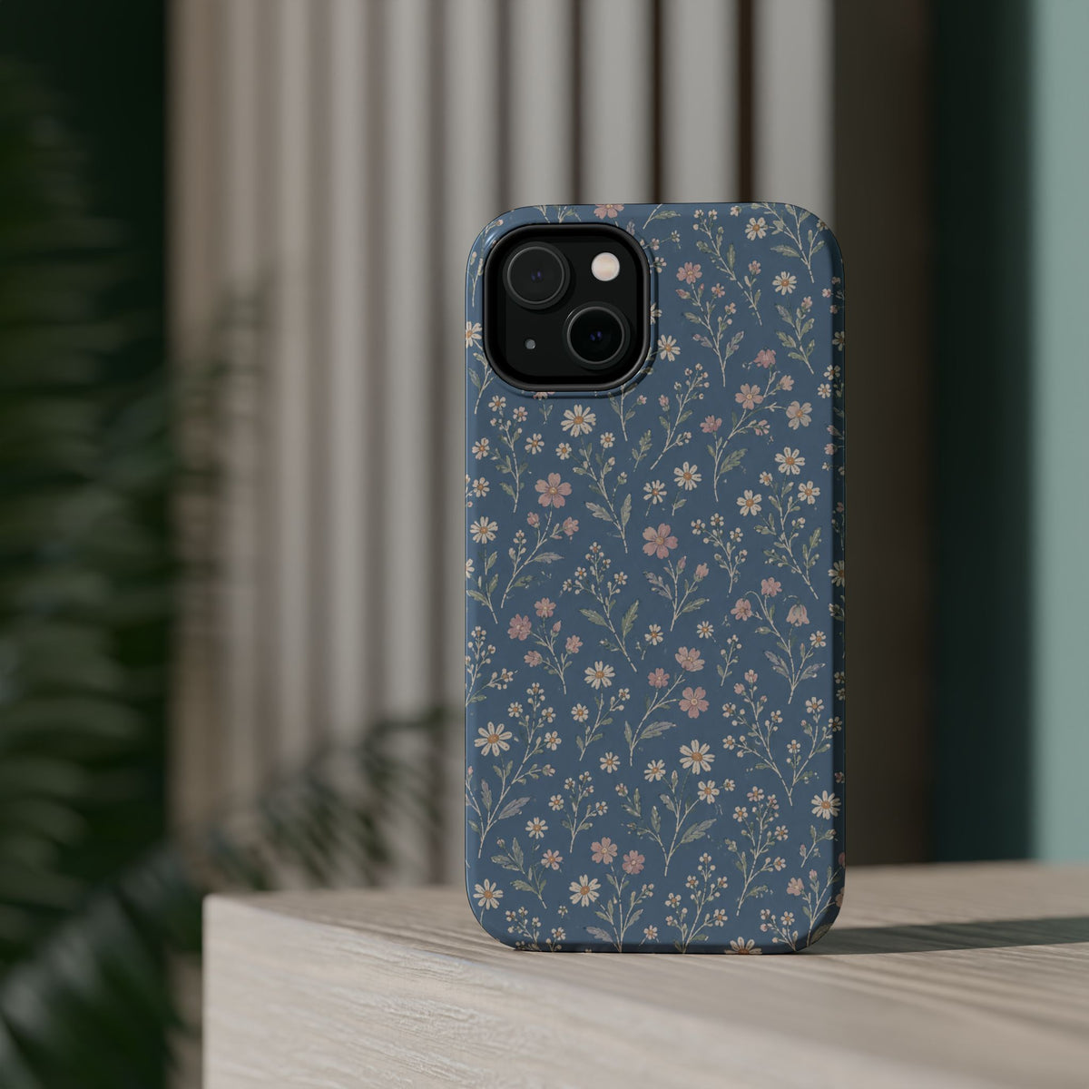 Denim Wildflowers MagSafe Phone Case, glossy diagonal dual-camera model, rear view on a tabletop