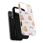 Two iPhone cases for iPhone 14 Pro Max showing size variant, one black and one white with teddy bear and bow pattern