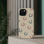 Prairie Horseshoes MagSafe Phone Case, glossy diagonal dual-camera model, rear view on a tabletop