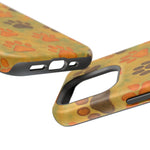 Close-up of two camouflage phone cases with orange and brown paw print design, showing variant size and port cutouts
