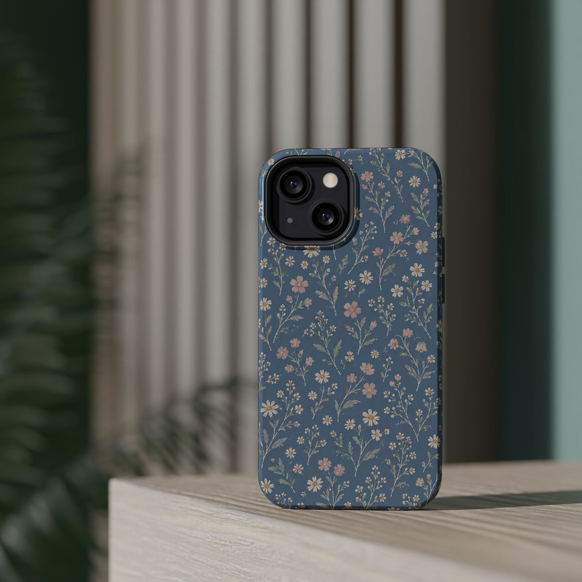 Denim Wildflowers MagSafe Phone Case, glossy diagonal dual-camera model, rear view on a tabletop