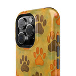 Close-up of phone case with large camera cutout, featuring brown and orange paw print pattern on mustard background