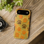 iPhone 13 Mini phone case with orange and brown paw print pattern on yellow-green background showing compact variant size