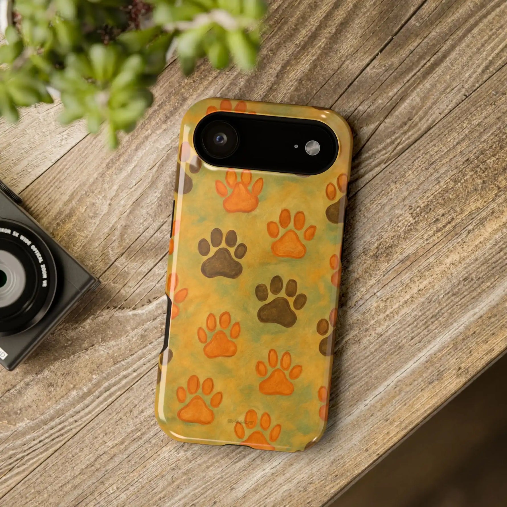 iPhone 13 Mini phone case with orange and brown paw print pattern on yellow-green background showing compact variant size