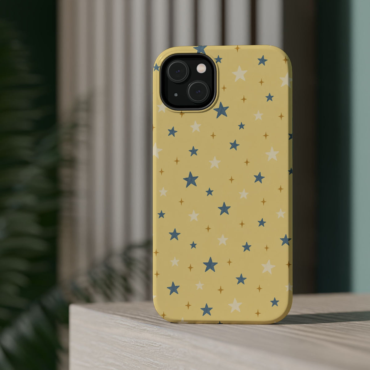 Prairie Stars – Yellow and Blue Star MagSafe Phone Case, glossy diagonal dual-camera model, rear view on a tabletop