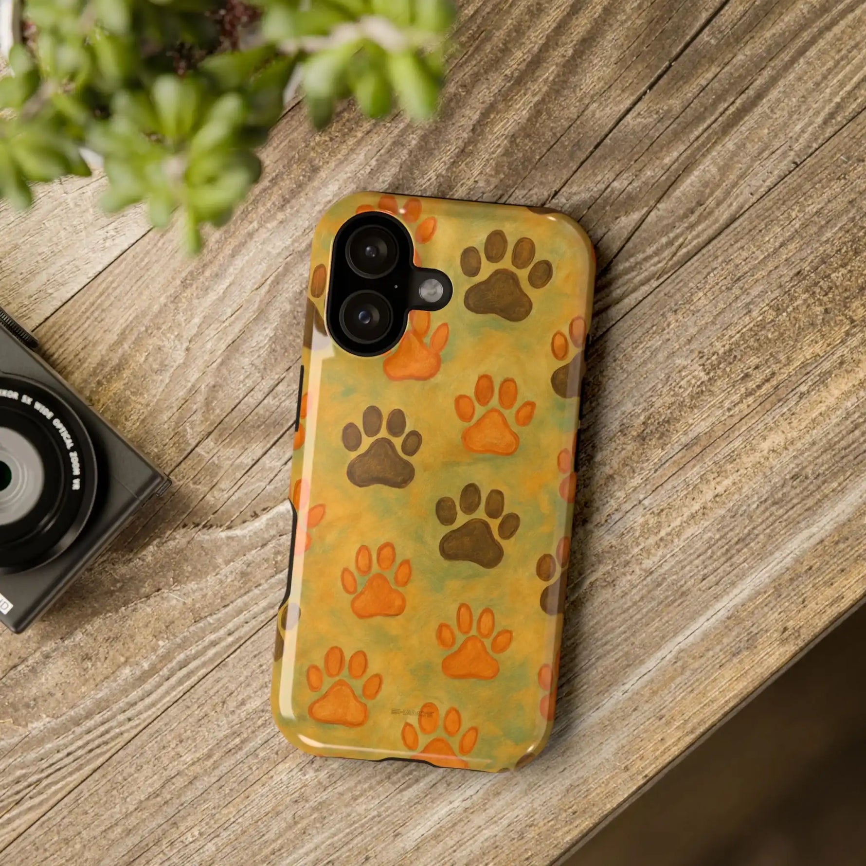iPhone 12/13/14 case with orange and brown paw print pattern on wood surface showing camera size variant