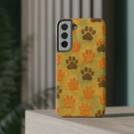 Samsung phone case with yellow background and brown and orange paw print pattern, showing triple camera