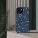 Lasso Hearts – Blue Western Heart MagSafe Phone Case, glossy diagonal dual-camera model, rear view on a tabletop