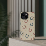 Prairie Horseshoes MagSafe Phone Case, glossy diagonal dual-camera model, rear view on a tabletop