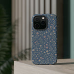 Denim Wildflowers MagSafe Phone Case, glossy square triple-camera Pro model, rear view on a tabletop