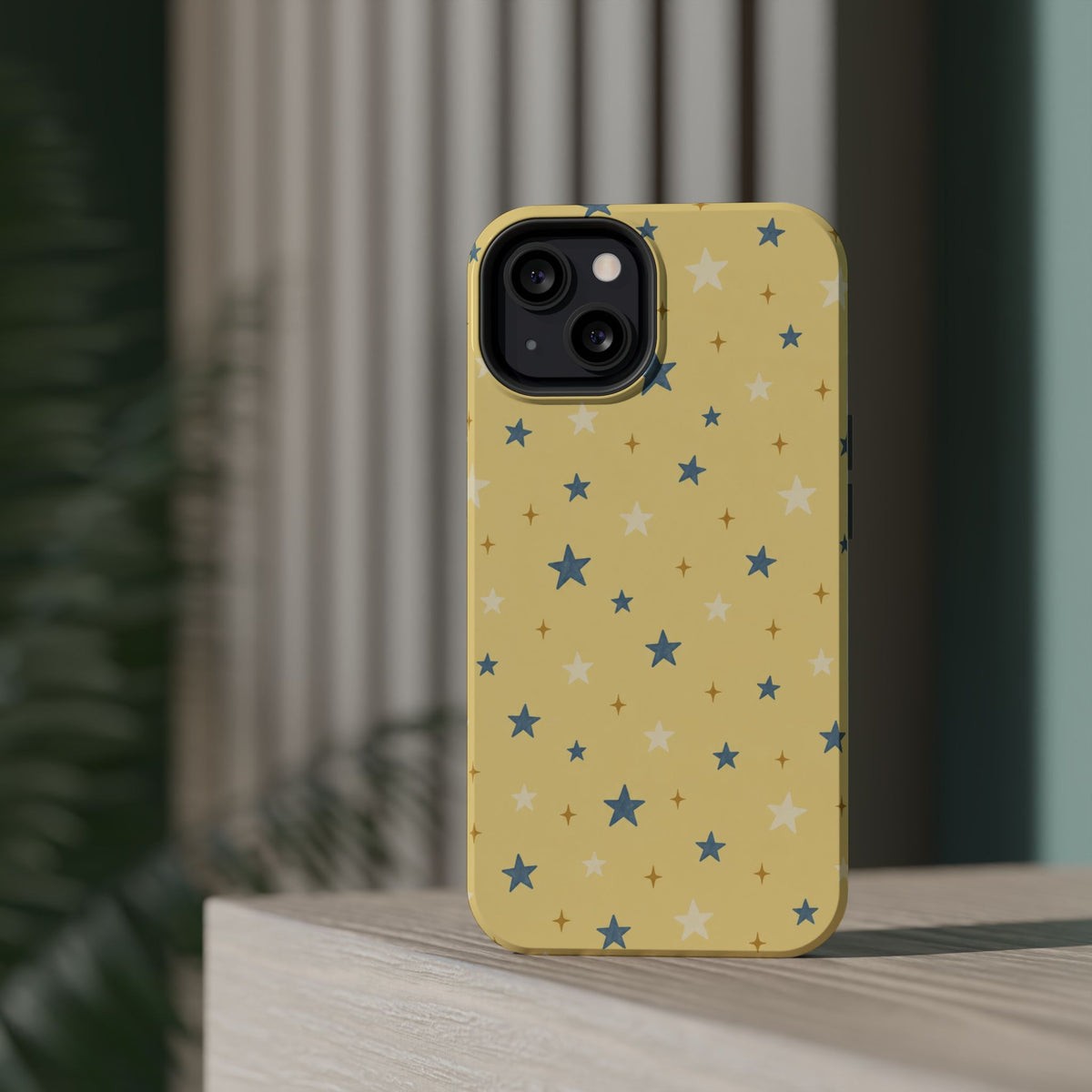 Prairie Stars – Yellow and Blue Star MagSafe Phone Case, glossy diagonal dual-camera model, rear view on a tabletop