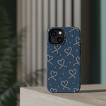 Lasso Hearts – Blue Western Heart MagSafe Phone Case, glossy diagonal dual-camera model, rear view on a tabletop