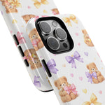 Close-up of two iPhone cases in different sizes with teddy bear and colorful bow pattern on white background