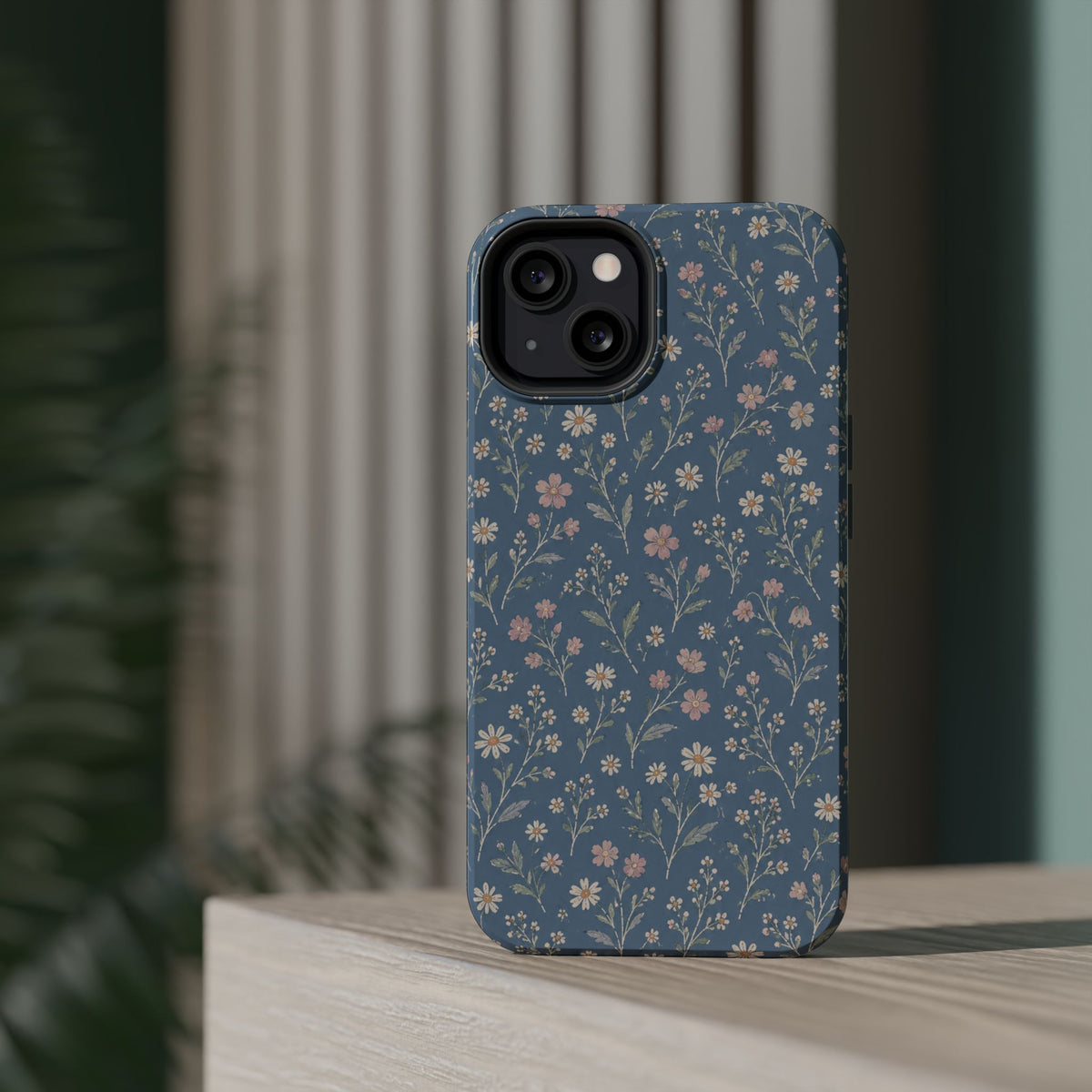 Denim Wildflowers MagSafe Phone Case, glossy diagonal dual-camera model, rear view on a tabletop