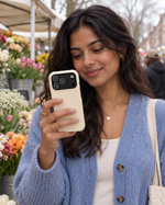 Woman holding a buttercream phone case at an outdoor flower market