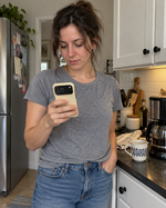 Woman checking her phone in a buttercream case beside a kitchen counter