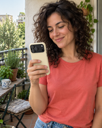 Woman smiling at her phone in a buttercream case on a balcony