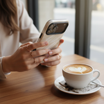 Person holding a white silk-and-gold wide-camera case at a cafe #iphone-17-pro-max