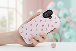 Cherry-pattern pink vertical dual-camera case held over a tabletop #iphone-16