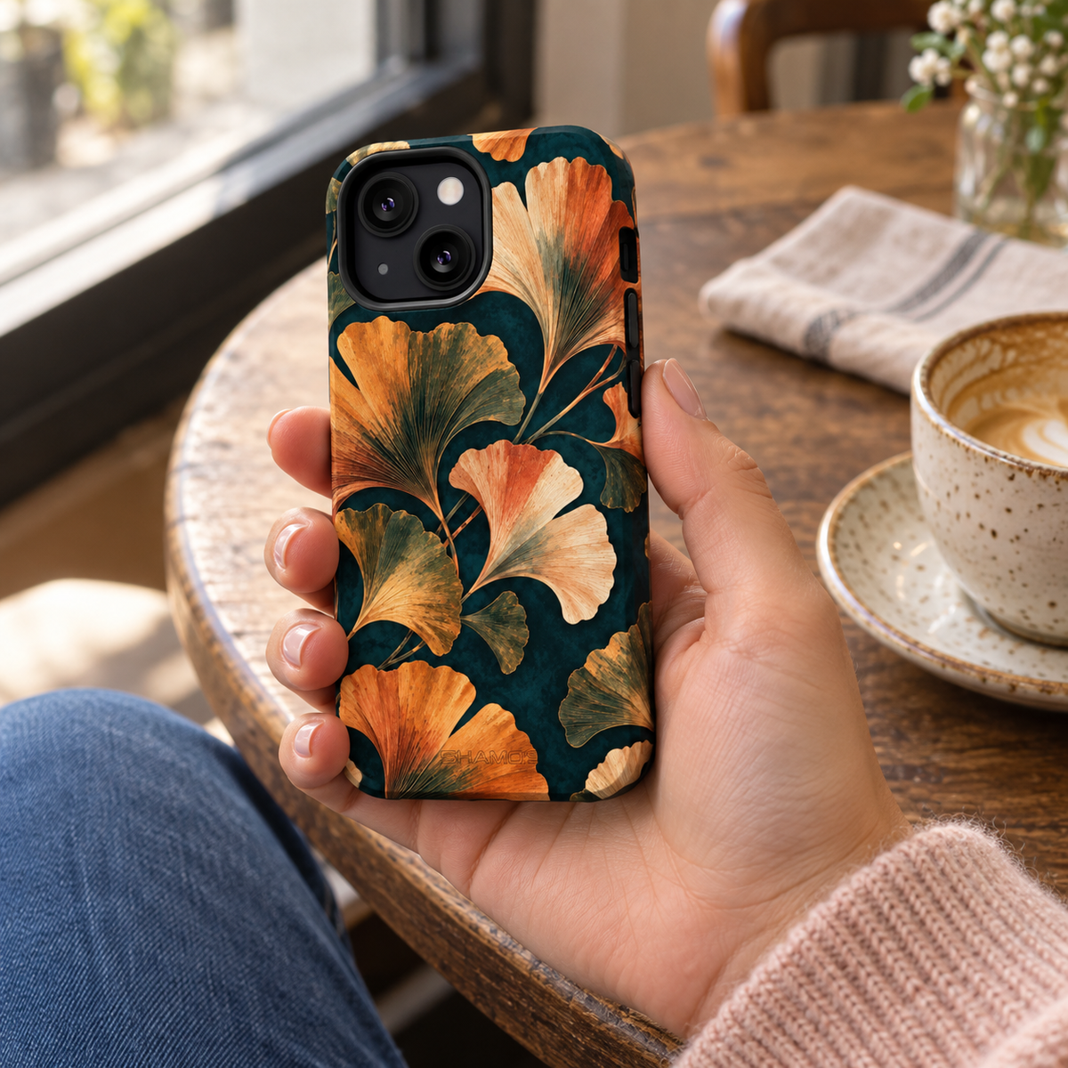 Adult woman holding the Nocturne Ginkgo iPhone 13 Mini case at a cafe #iphone-13-mini