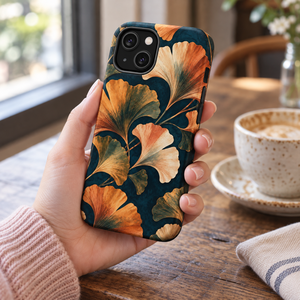 Adult woman holding the Nocturne Ginkgo iPhone 14 case at a cafe #iphone-14