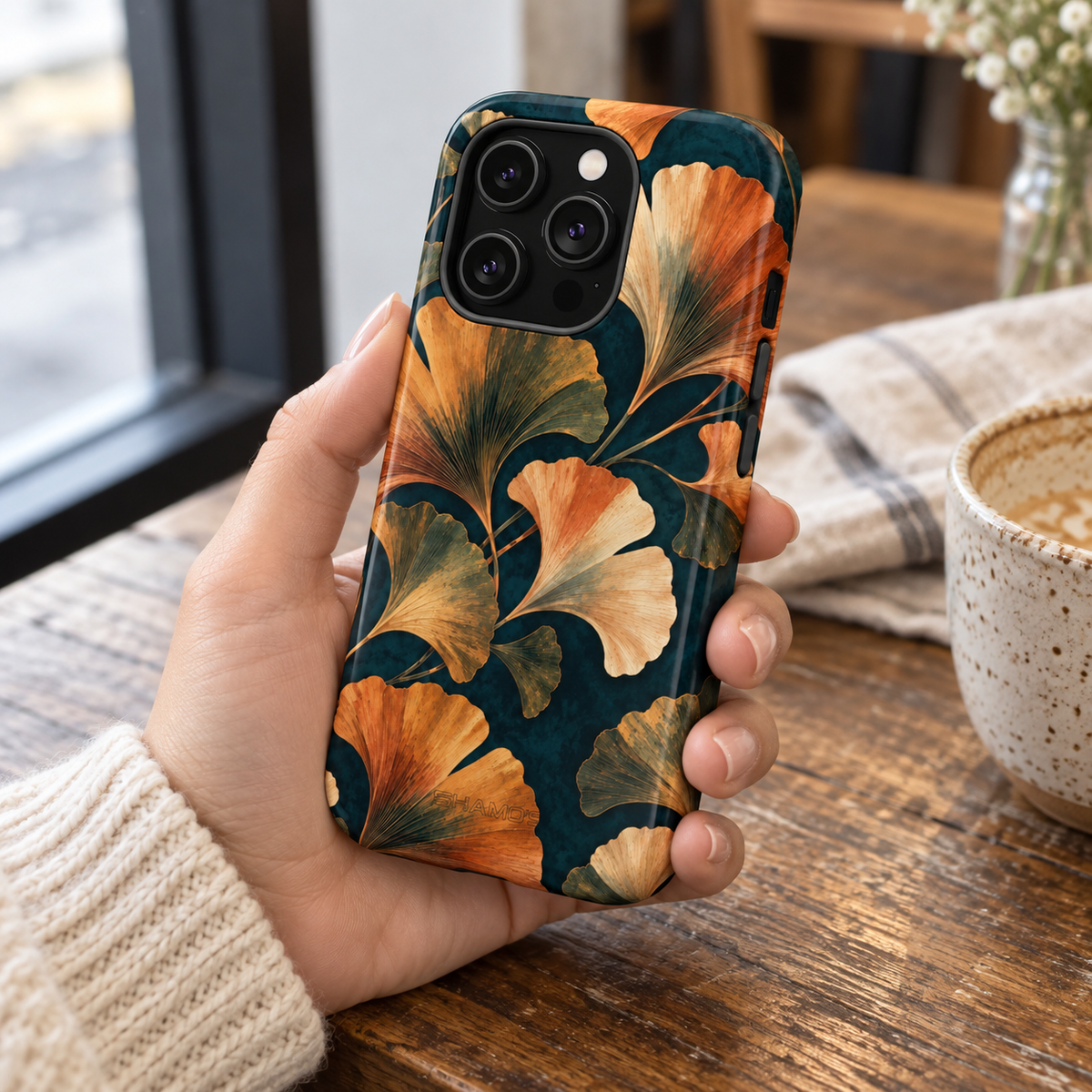 Adult woman holding the Nocturne Ginkgo iPhone 14 Pro case at a cafe #iphone-14-pro