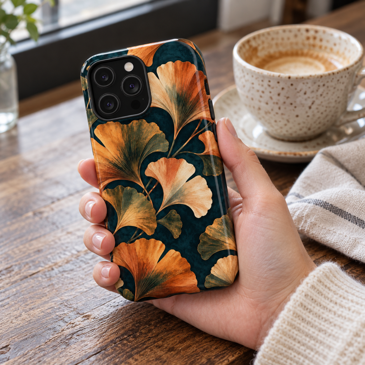 Adult woman holding the Nocturne Ginkgo iPhone 14 Pro Max case at a cafe #iphone-14-pro-max