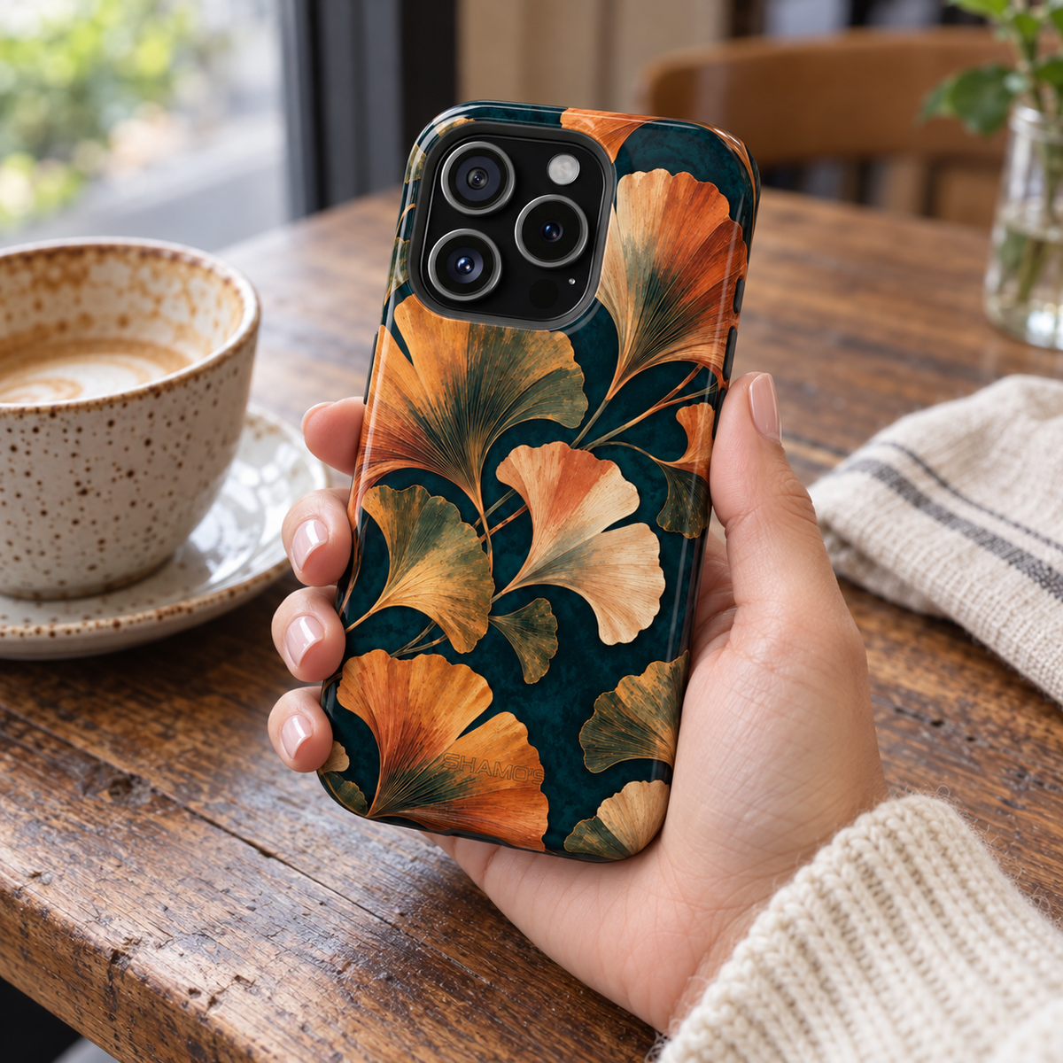 Adult woman holding the Nocturne Ginkgo iPhone 15 Pro case at a cafe #iphone-15-pro