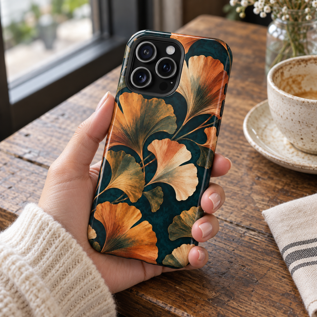 Adult woman holding the Nocturne Ginkgo iPhone 15 Pro Max case at a cafe #iphone-15-pro-max