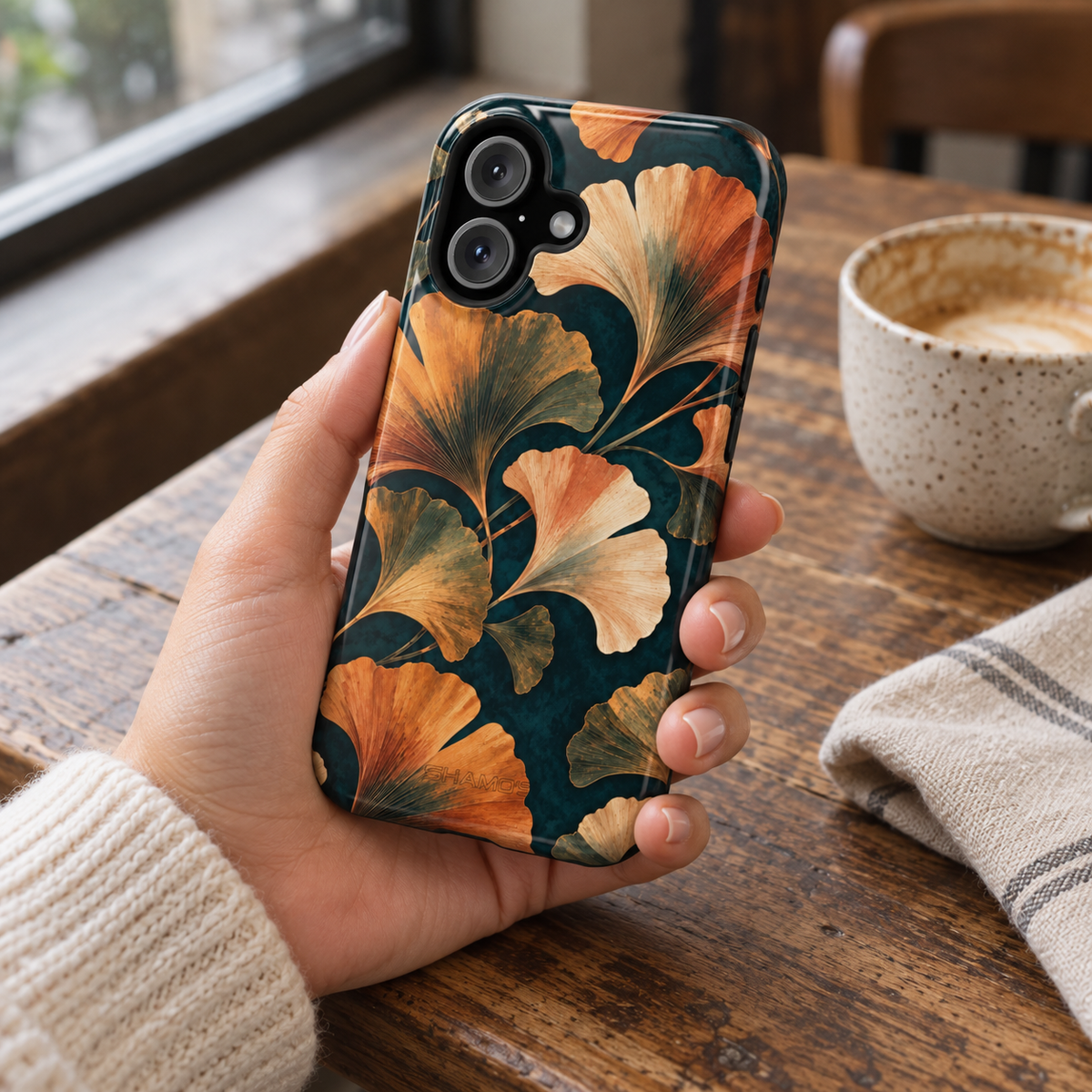 Adult woman holding the Nocturne Ginkgo iPhone 16 case at a cafe #iphone-16