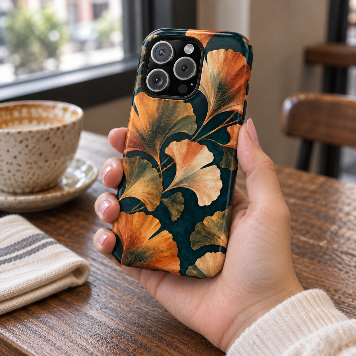 Adult woman holding the Nocturne Ginkgo iPhone 16 Pro case at a cafe #iphone-16-pro