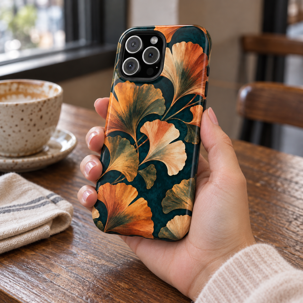 Adult woman holding the Nocturne Ginkgo iPhone 16 Pro Max case at a cafe #iphone-16-pro-max