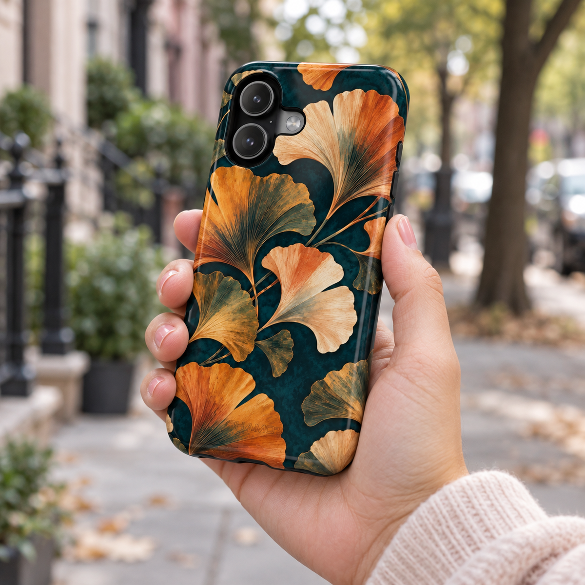 Adult woman holding the Nocturne Ginkgo iPhone 17 case outdoors #iphone-17