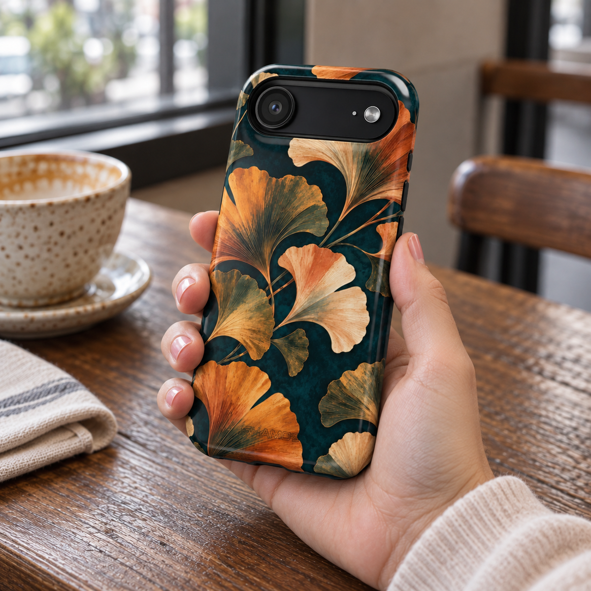 Adult woman holding the Nocturne Ginkgo iPhone 17 Air case at a cafe #iphone-17-air