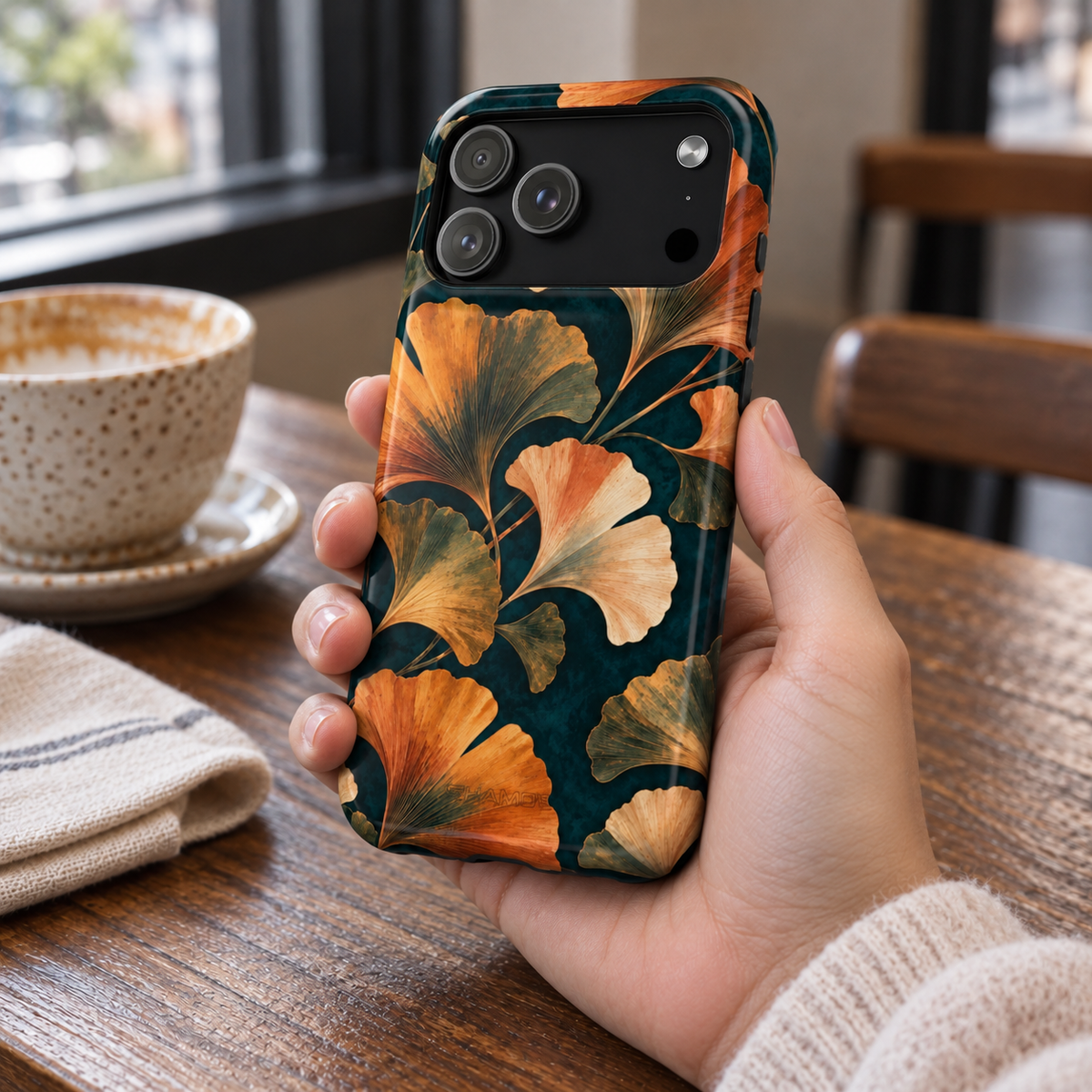 Adult woman holding the Nocturne Ginkgo iPhone 17 Pro Max case at a cafe #iphone-17-pro-max